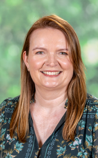 Staff member portrait photographed indoors against a softly blurred green background.